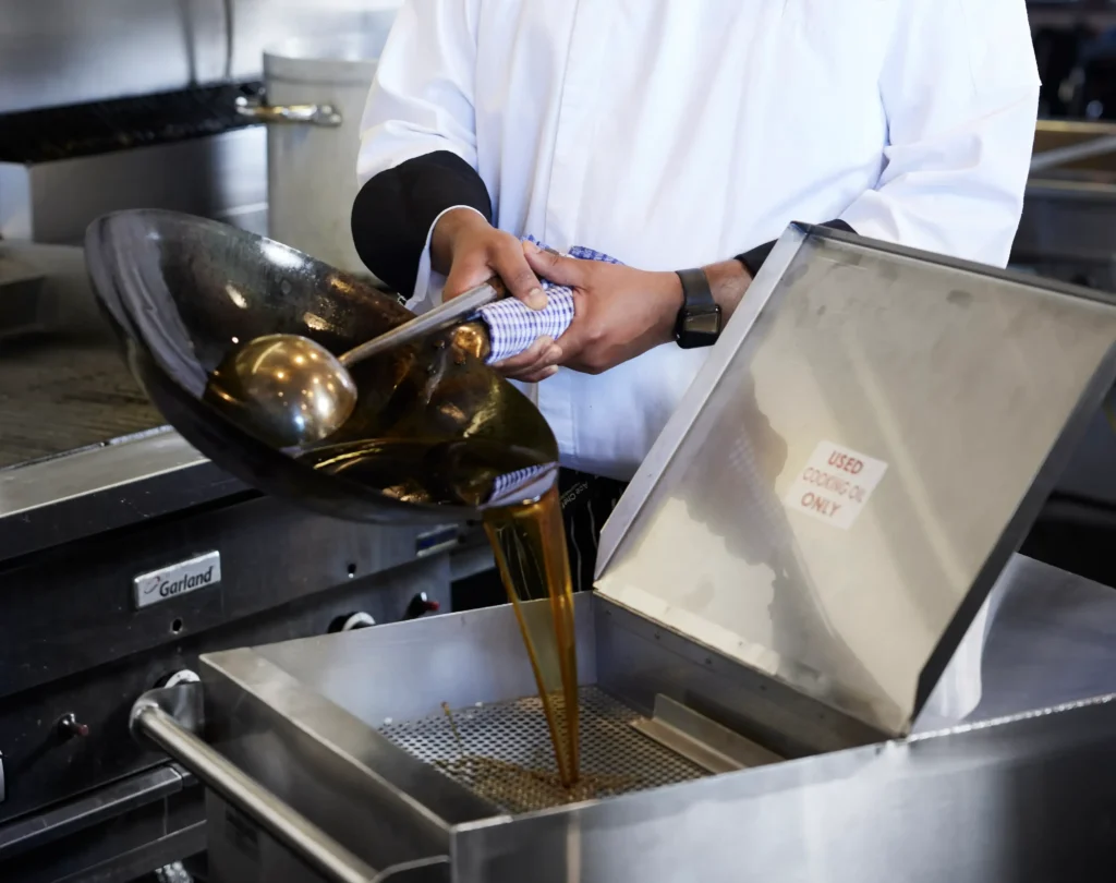 Orange County kitchen staff pouring used cooking oil into a storage container